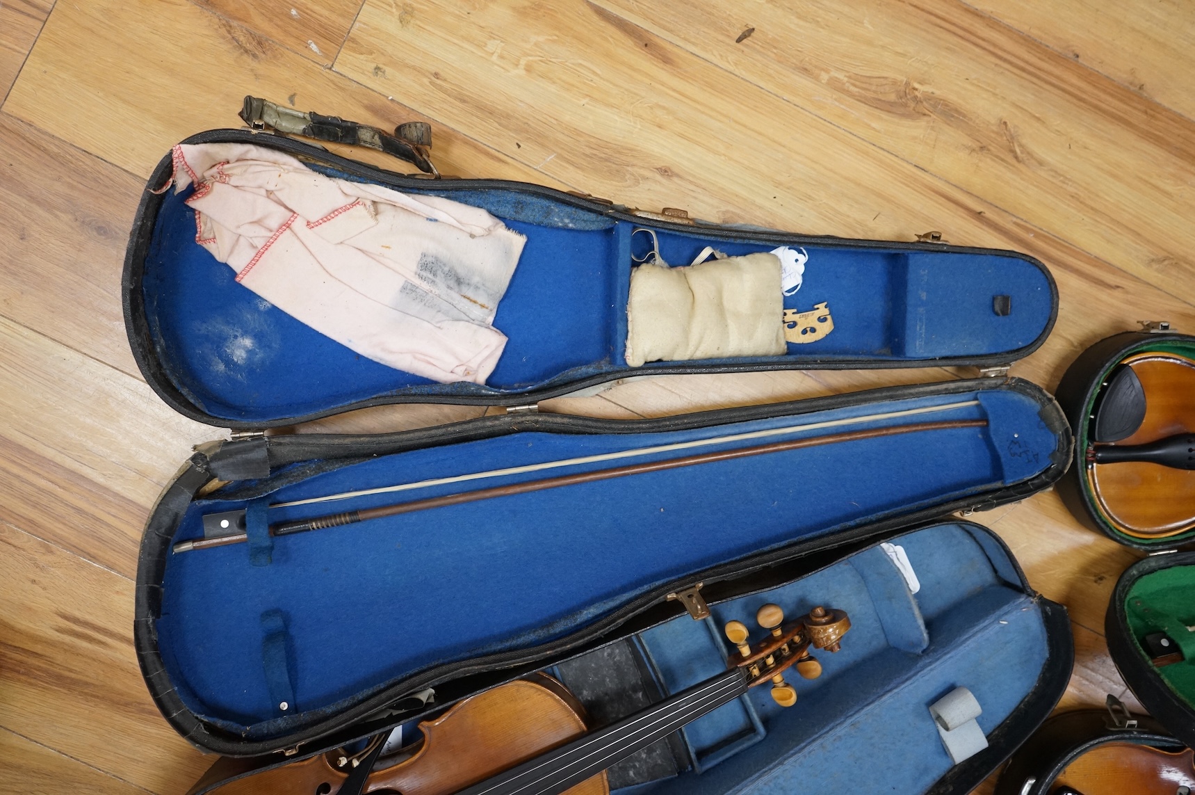Five cased 20th century violins, including; a German violin, two Czech violins, a three-quarter size violin with a label for Bienfait, and a Romanian quarter size violin, all in cases or the remains of cases.